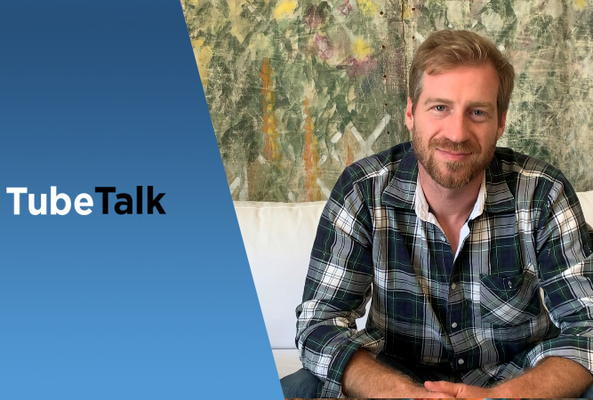 Man in plaid shirt sitting on white couch with TubeTalk logo on blue background.